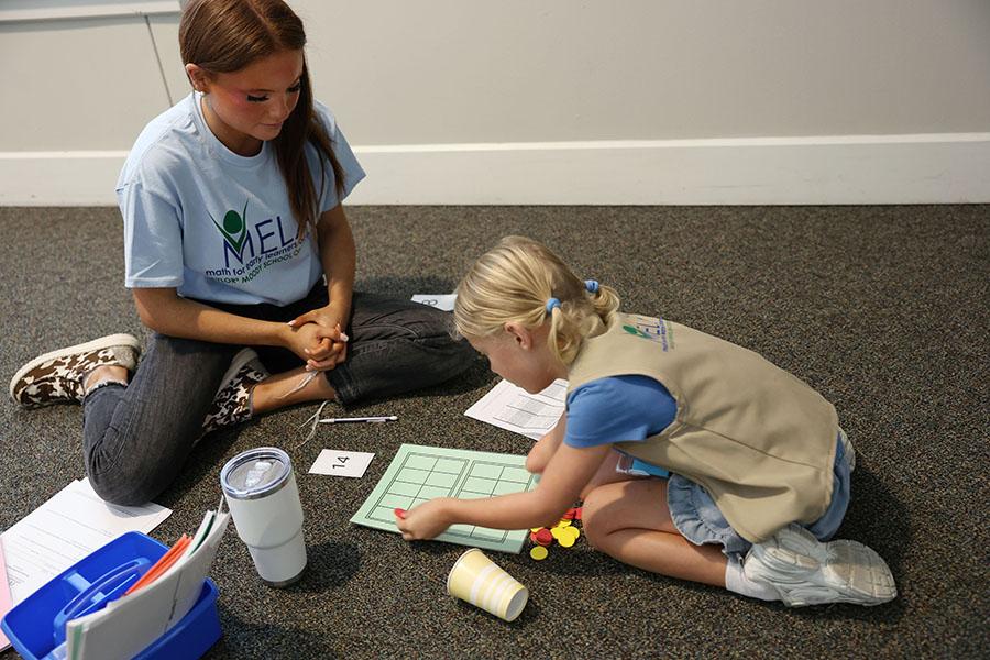 Baylor education student helps a young child who is counting discs up to 14